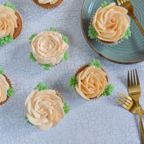 rose pistachio buttercream flower cupcakes on a white backdrop and one on a green plate