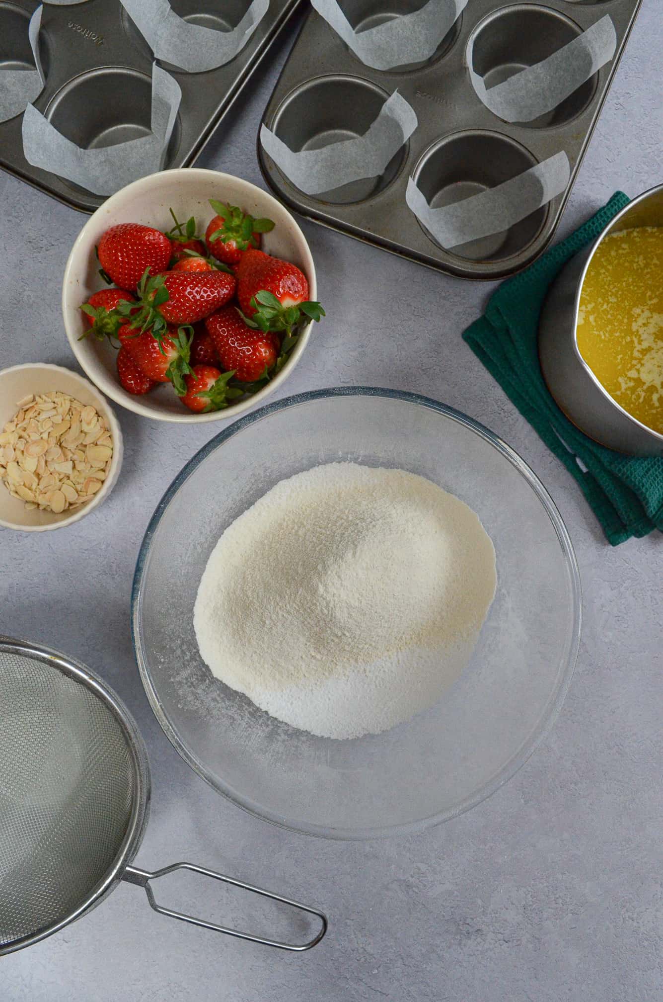 icing sugar and flour together in bowl, with strawberries and flaked almonds to the side