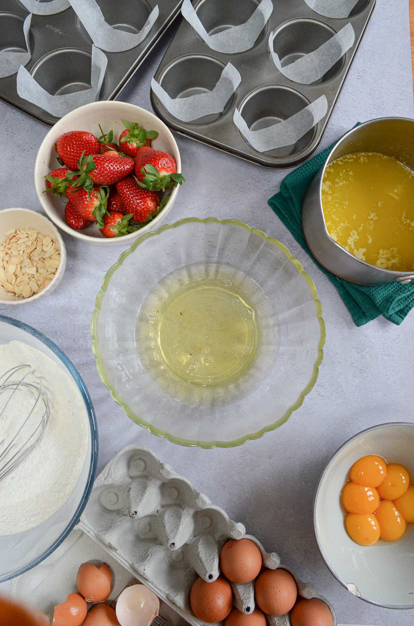 egg whites in large bowl with strawberries and other ingredients surrounding