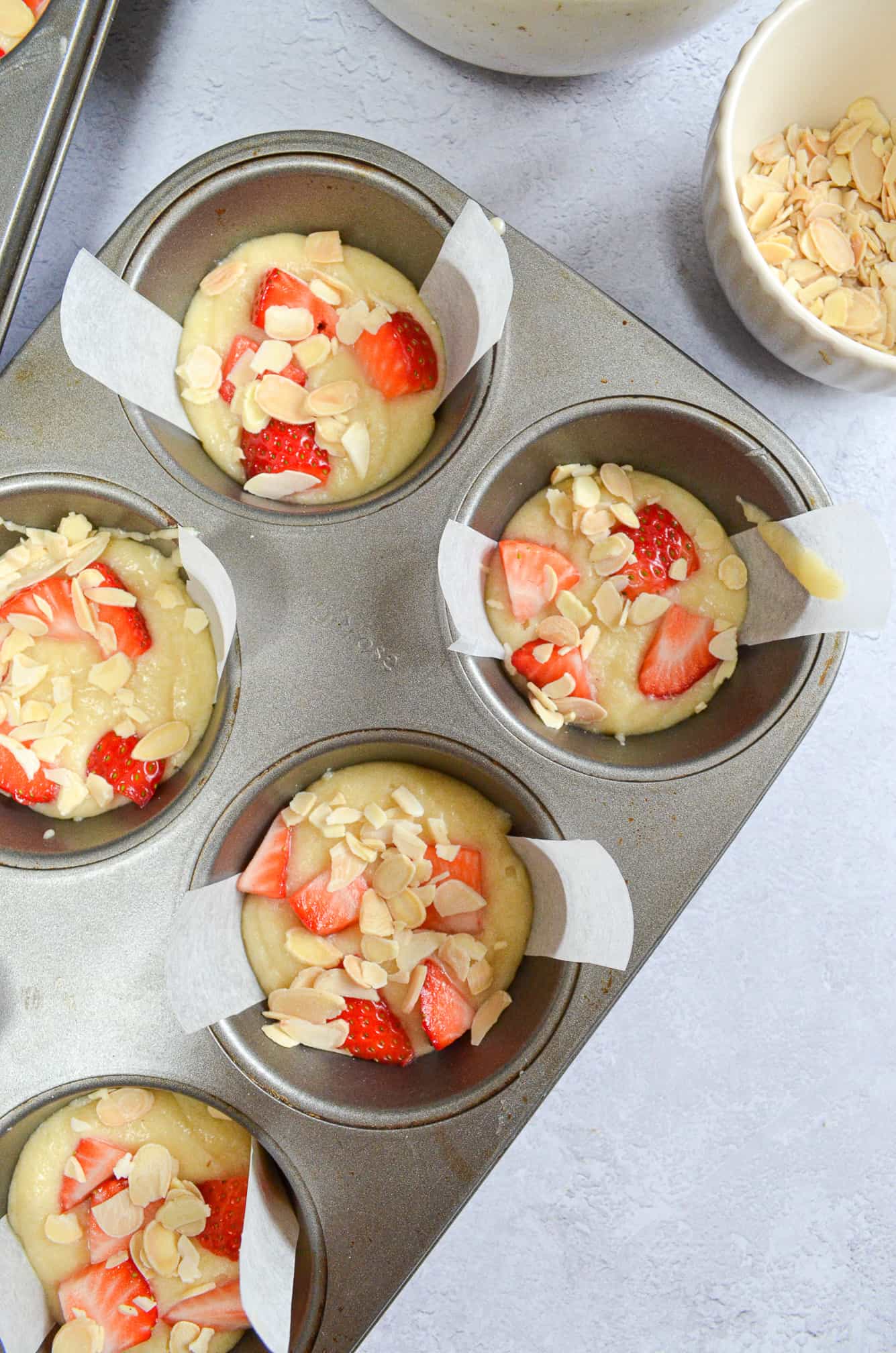 friand batter in muffin tin with strawberries